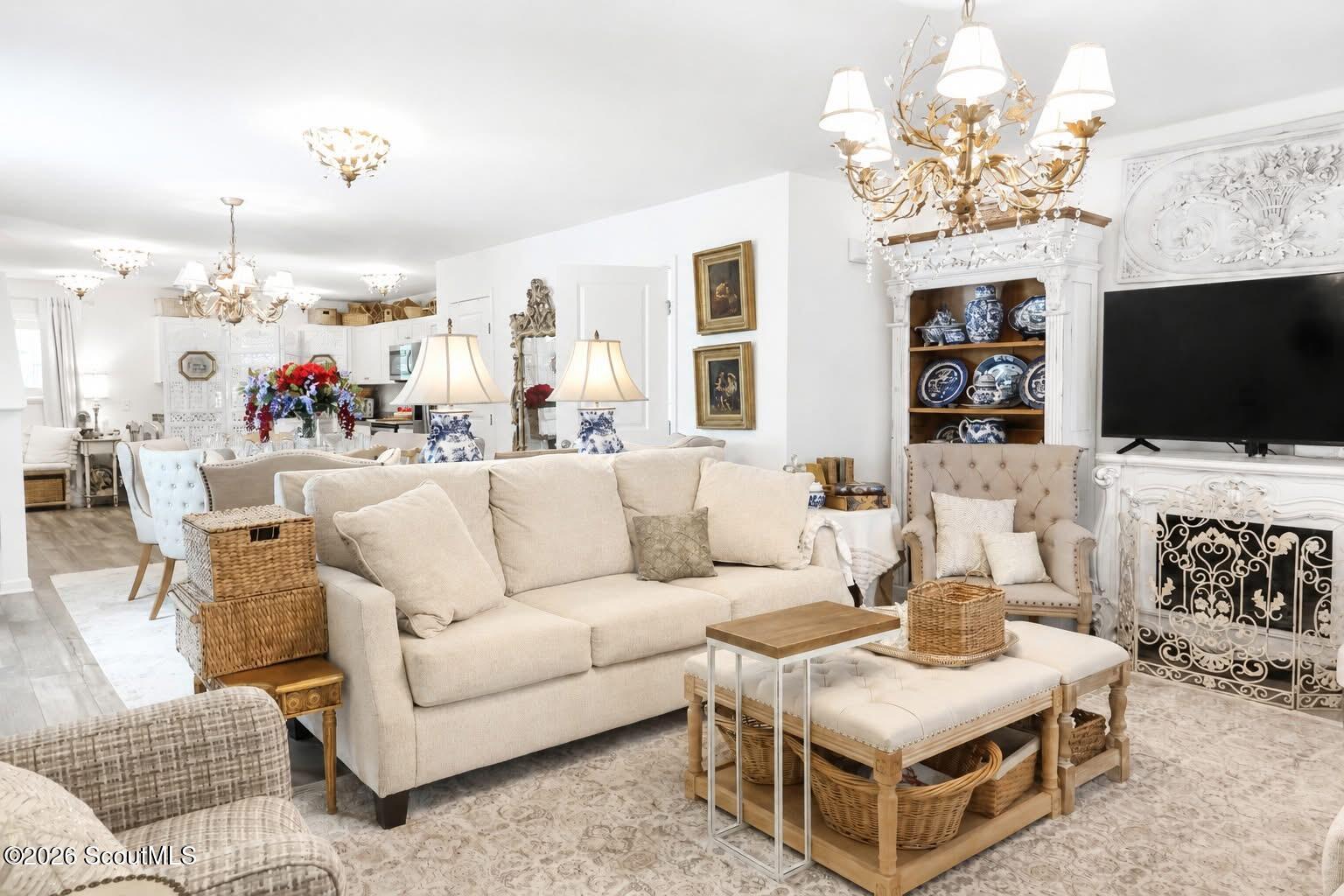 Furnished living room with a cream sectional, ornate white fireplace, television, and blue-and-white china display.