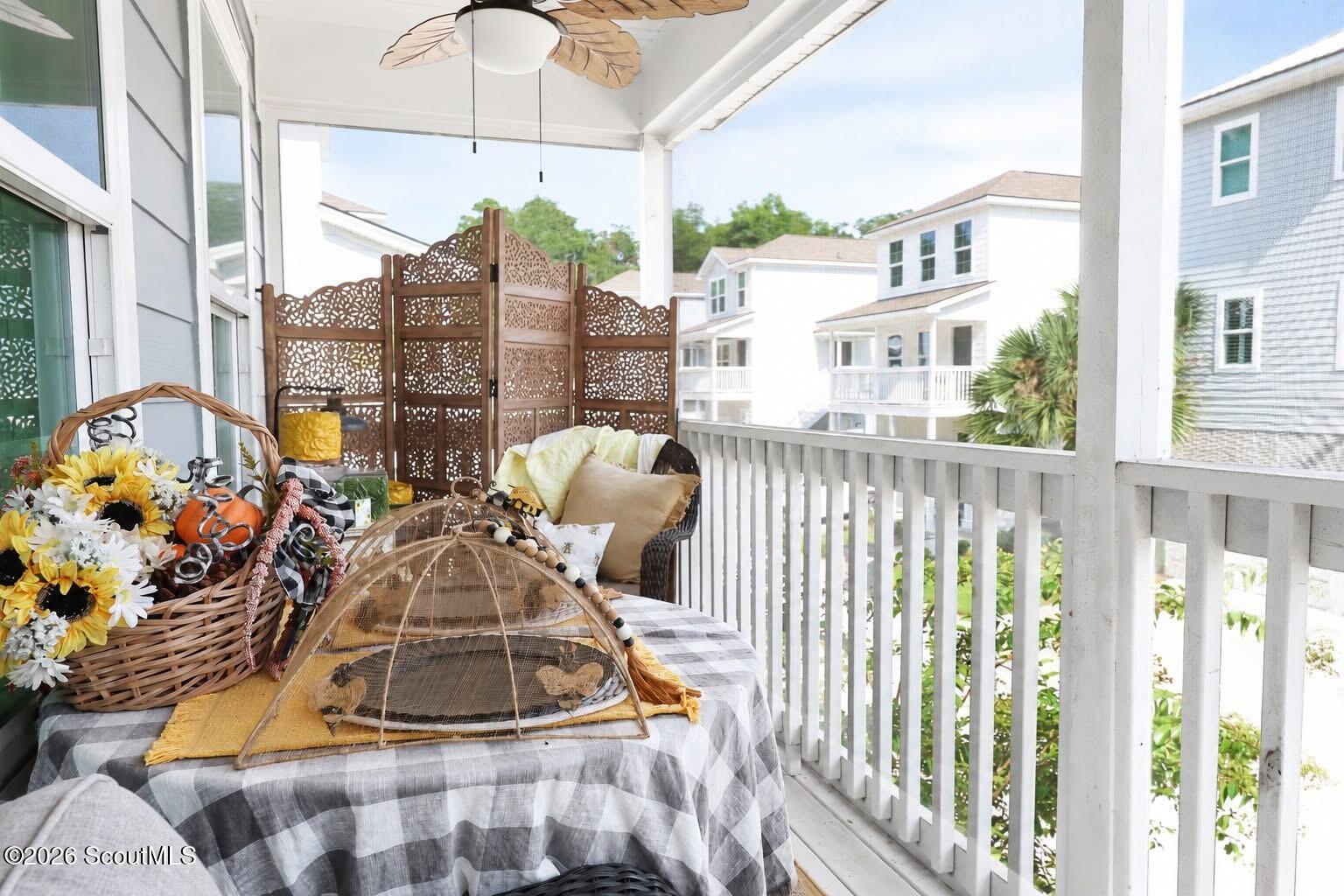 Covered porch with wicker seating, a decorative screen, and views of neighboring homes.