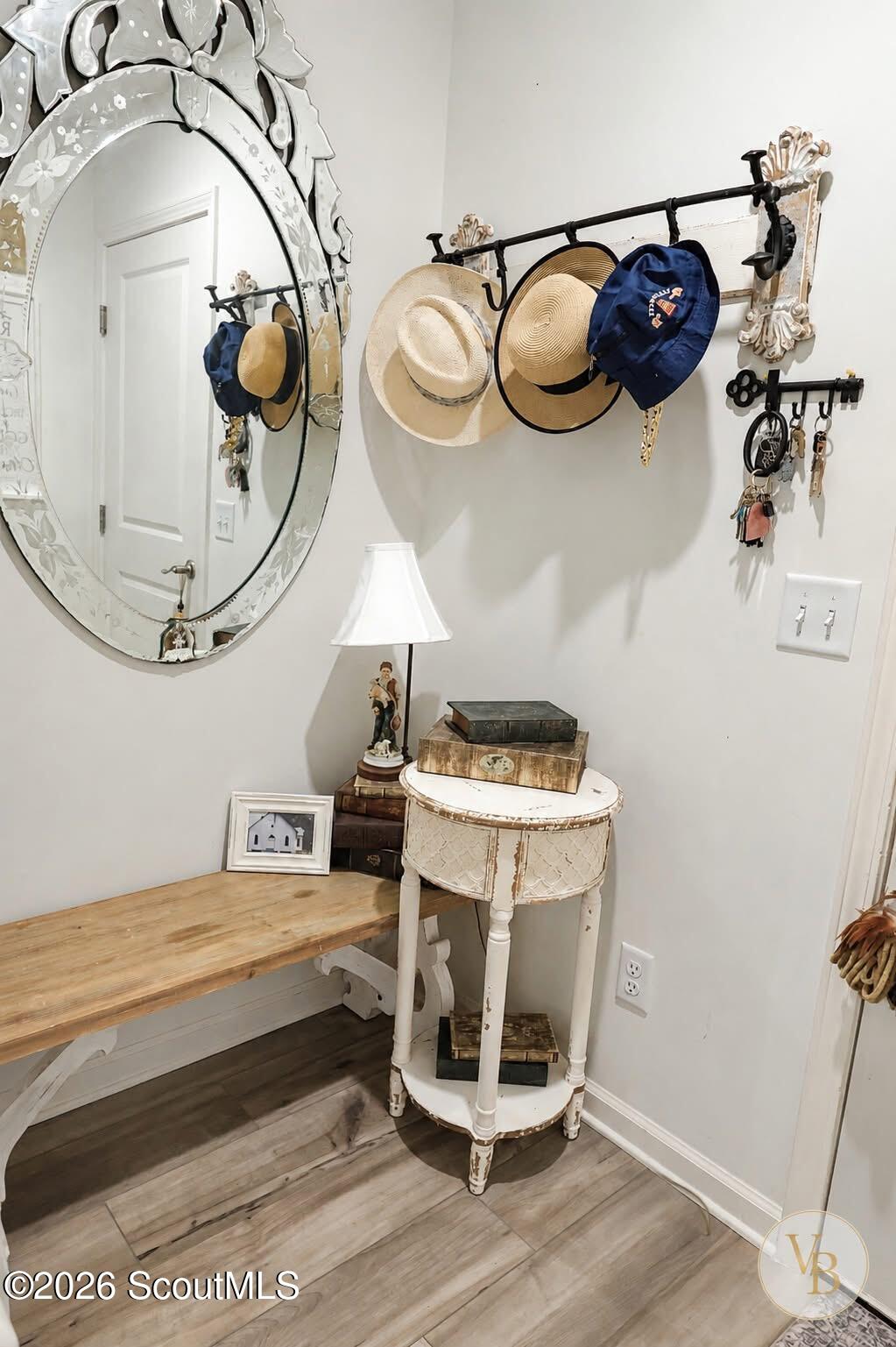 Entryway with an ornate oval mirror, hat rack, wooden bench, and distressed white table.