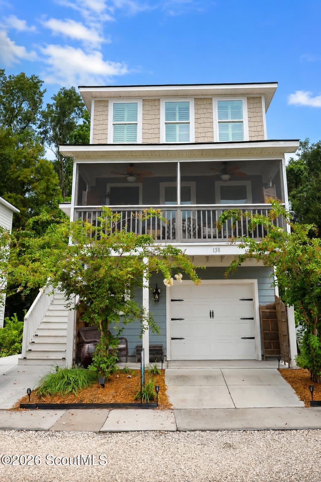 Raised two-story house with a screened porch, white garage door, and exterior staircase.