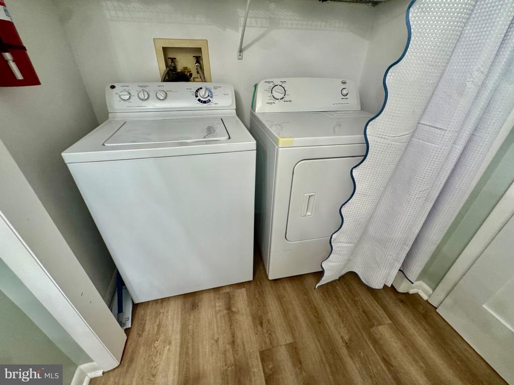 Laundry area with white washer and dryer behind a white curtain.