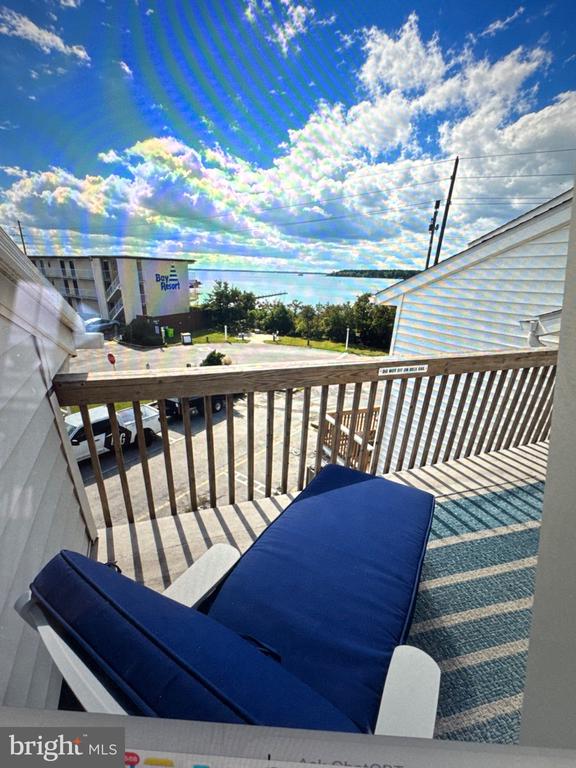 Balcony with blue lounge chairs and a distant water view.