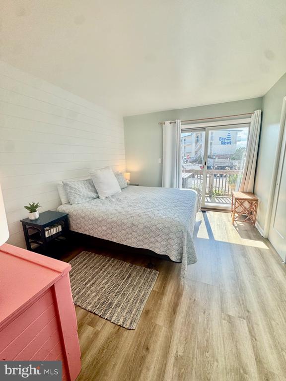 Bright bedroom with a patterned bed, white shiplap wall, and sliding glass doors to a balcony.