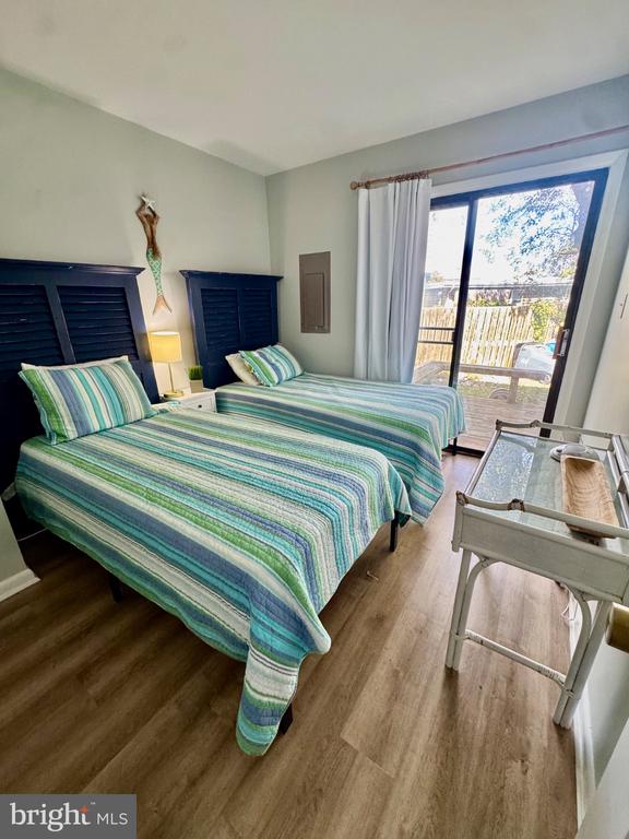 Bedroom with two striped twin beds and a sliding glass door to a balcony.