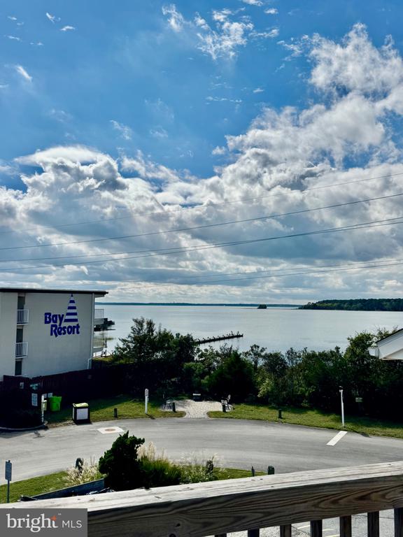 Bay view from a balcony, with the Bay Resort building, wooded shoreline, and railing in the foreground.