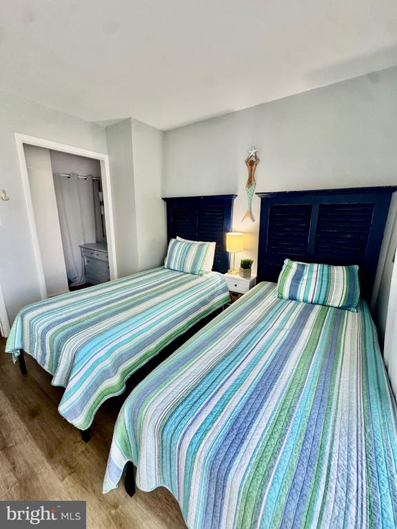 Bedroom with two twin beds in striped bedding and dark louvered headboards.