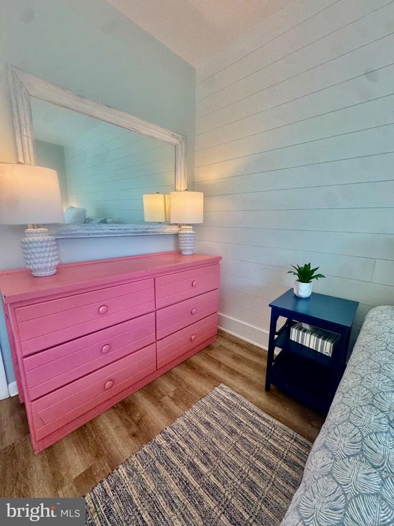 Bedroom with a bright pink dresser, large mirror, and dark blue bedside table.