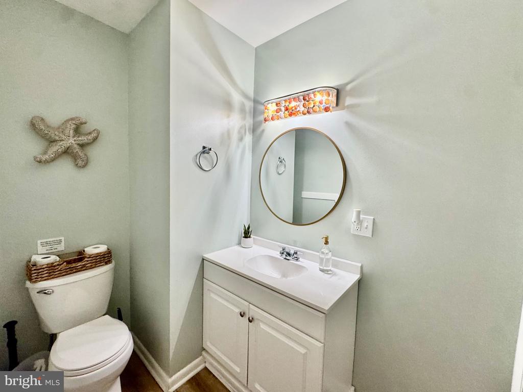 Bathroom with a white vanity, round gold-framed mirror, and colorful light fixture.