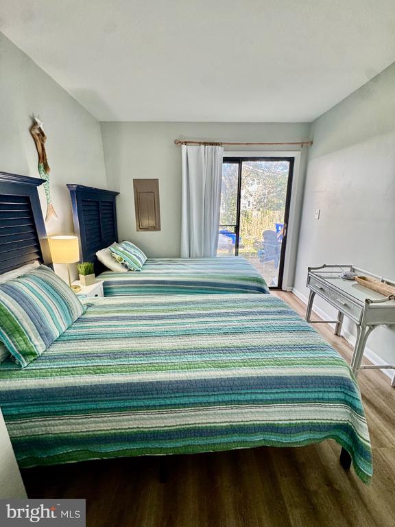 Bedroom with two green-and-blue striped beds and a sliding glass door.