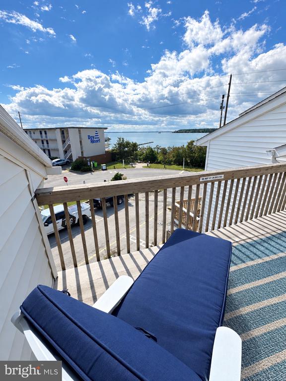 Furnished balcony with blue lounge chairs overlooking the water.