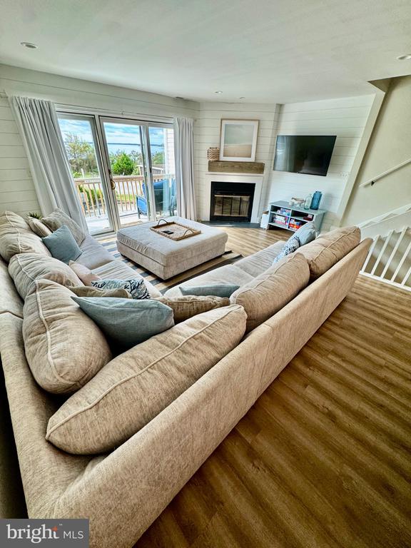 Living room with a beige sectional, fireplace, wall-mounted TV, and sliding glass doors to a balcony.