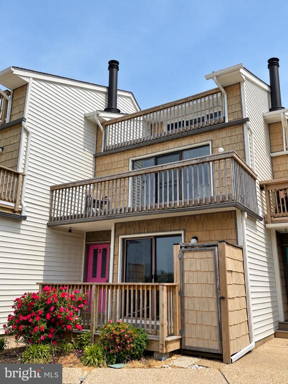 Multi-unit residence with cedar-shingle accents, two wooden decks, and a bright pink entry door.