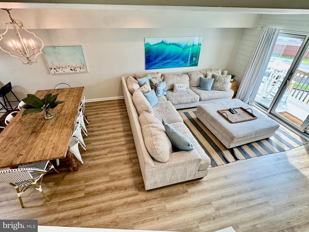 Furnished living and dining area with a cream sectional, rustic wood table, and sliding doors to a balcony.