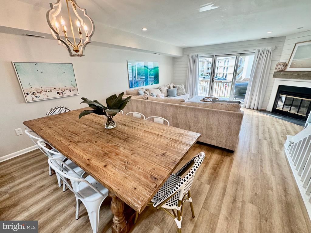 Open dining and living area with a rustic wood table, beige sectional, sliding glass doors, and fireplace.
