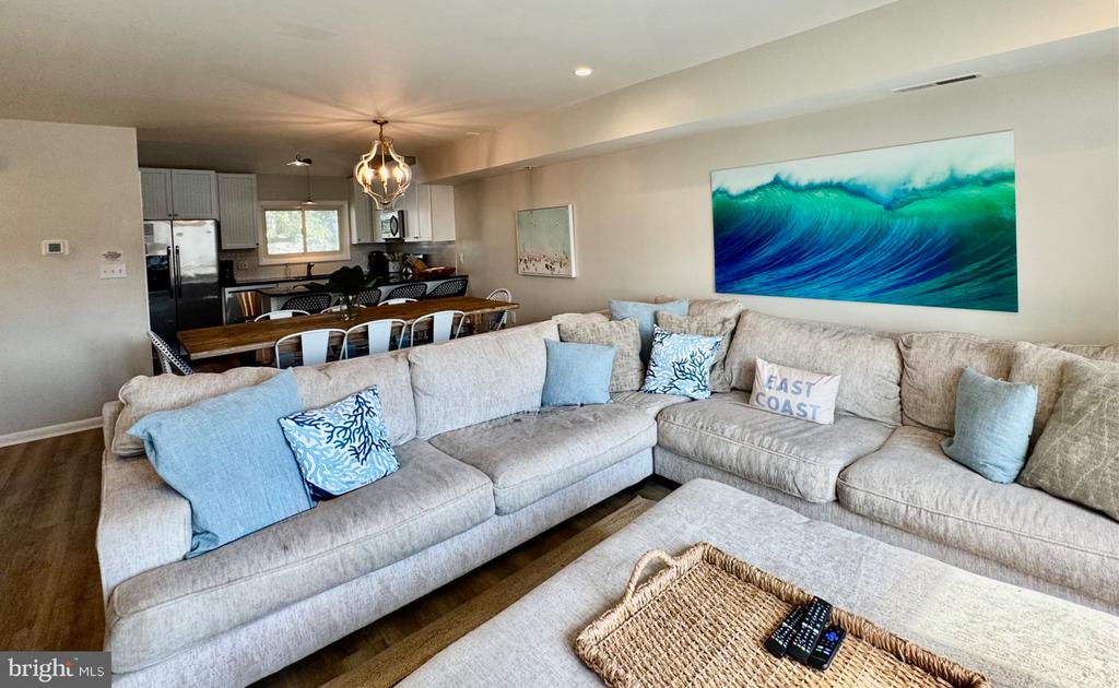 Open-plan living room with a large sectional, blue coastal accents, and the kitchen and dining area beyond.