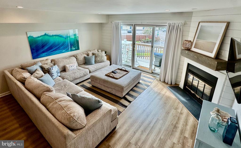 Living room with a beige sectional, fireplace, striped rug, and sliding doors to a deck.