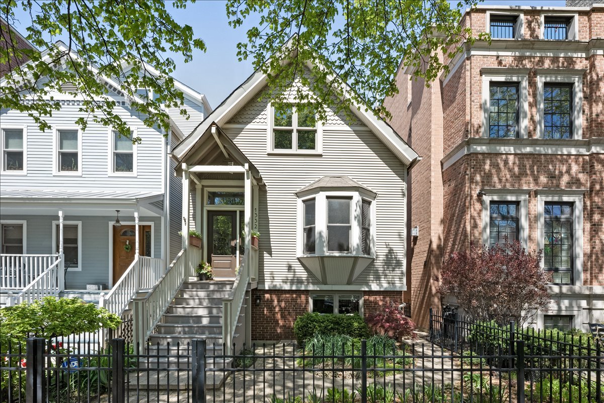 Gabled Chicago home with a raised entry, projecting bay window, and fenced front garden.