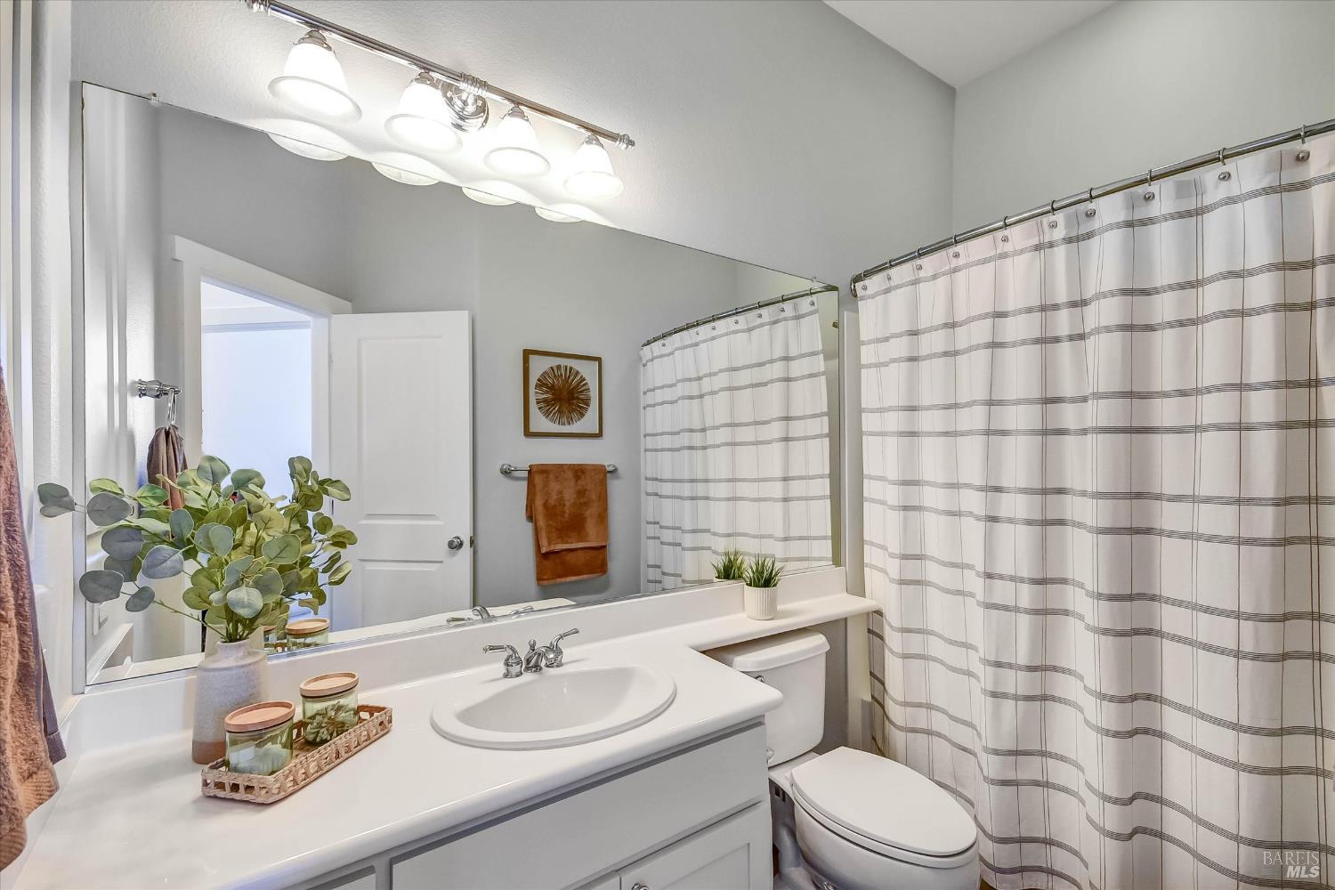 Bathroom with a white vanity, large mirror, and striped shower curtain.