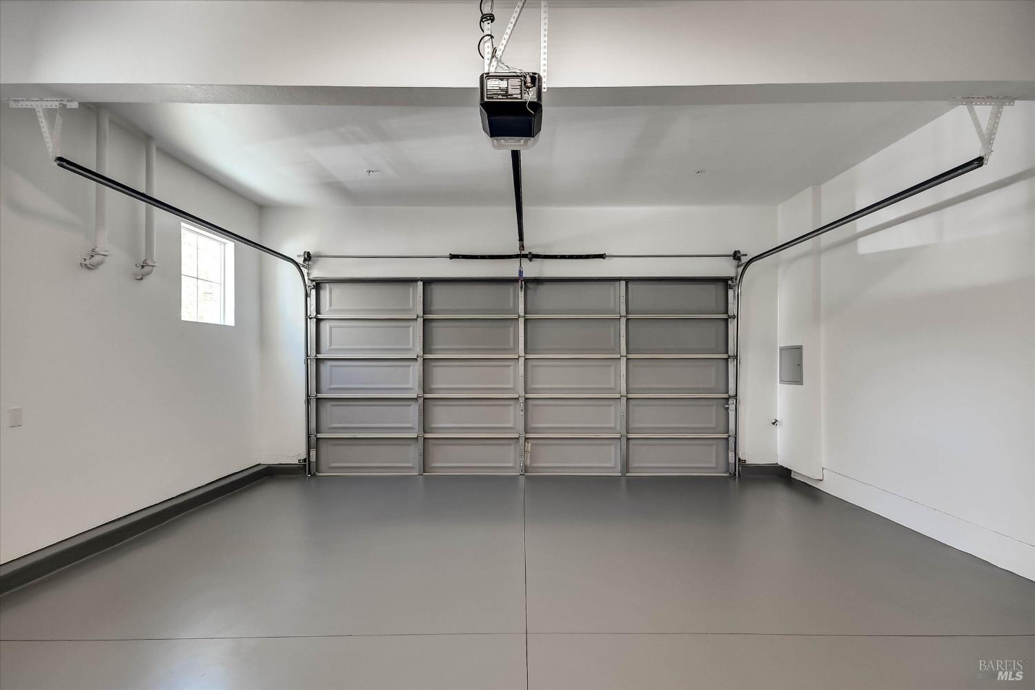 Empty garage with a smooth gray floor and closed sectional door.
