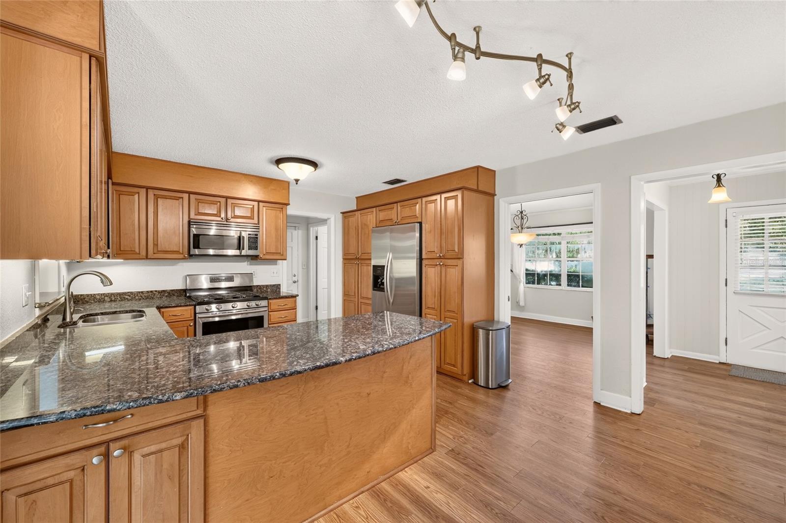 Kitchen with warm wood cabinets, granite countertops, a large island, and stainless steel appliances.