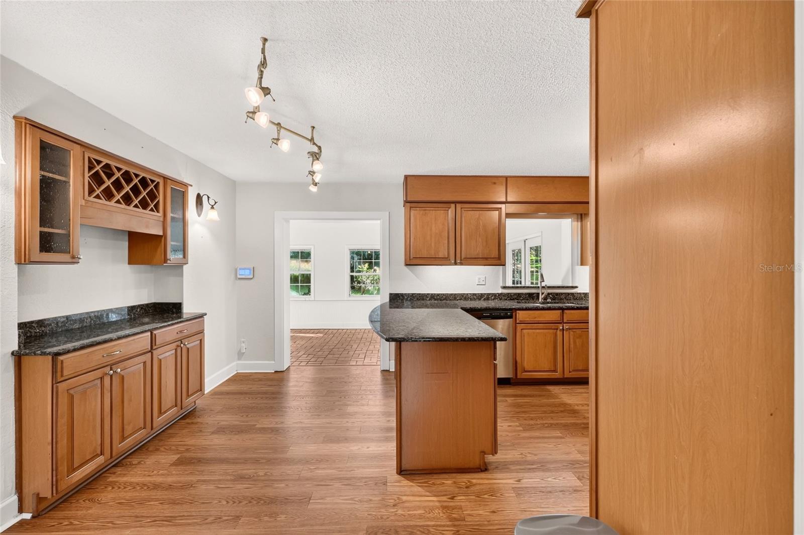 Kitchen with wood cabinetry, granite counters, a central island, and wood flooring.