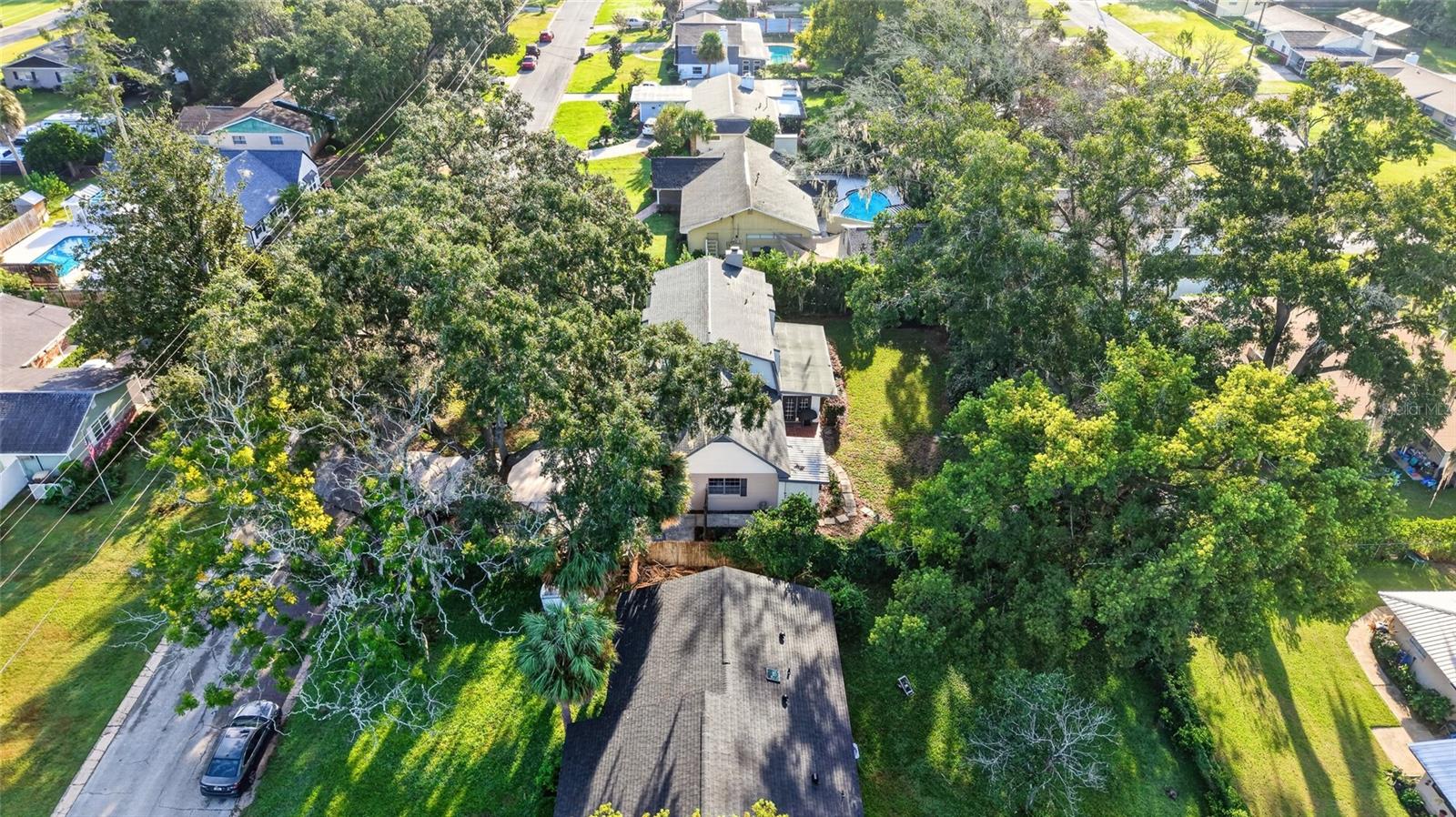 Aerial view of the home on a leafy lot among neighboring houses.