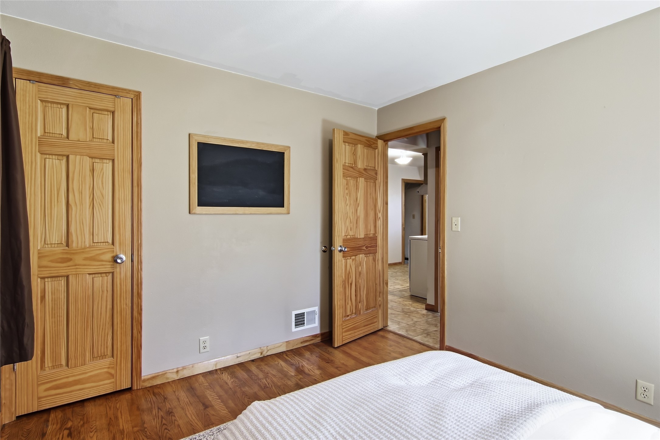 Bedroom with hardwood floors, paneled wood doors, and a framed chalkboard.