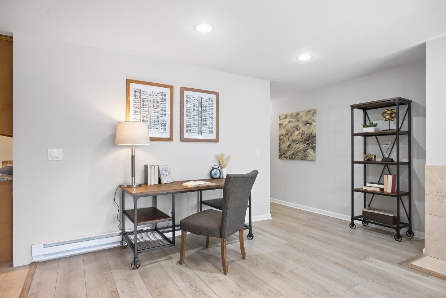 Staged home office with a wood desk, gray chair, and black open shelving.