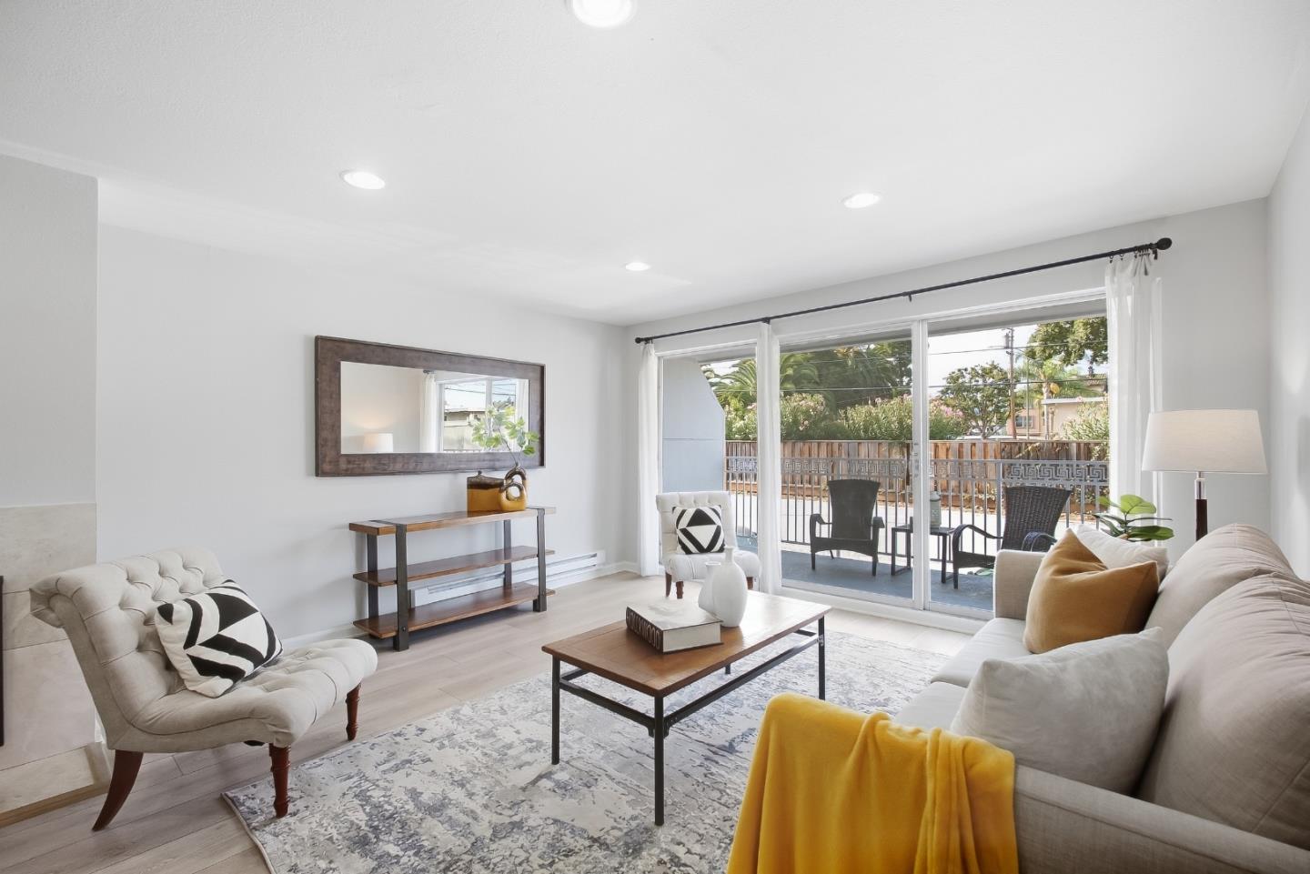 Living room with cream sofas and a patterned rug, opening onto a patio through sliding glass doors.