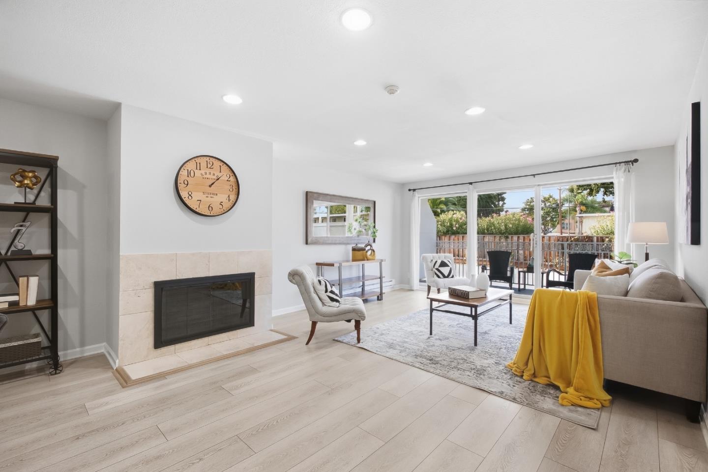 Living room with tiled fireplace, gray sofa, mustard throw, and sliding glass doors to a patio.