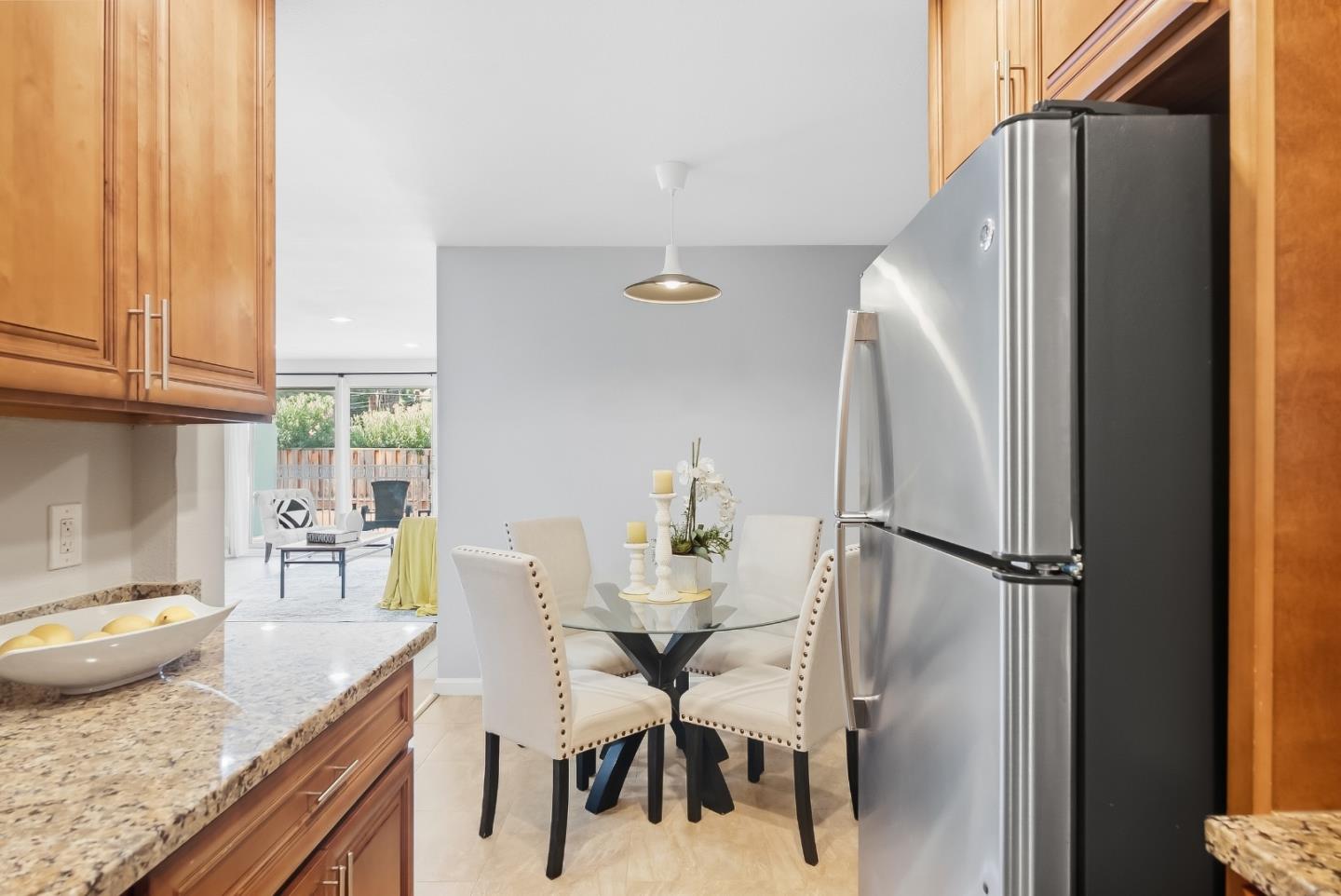 Kitchen and dining area with wood cabinets, granite counters, and a glass table beside sliding patio doors.