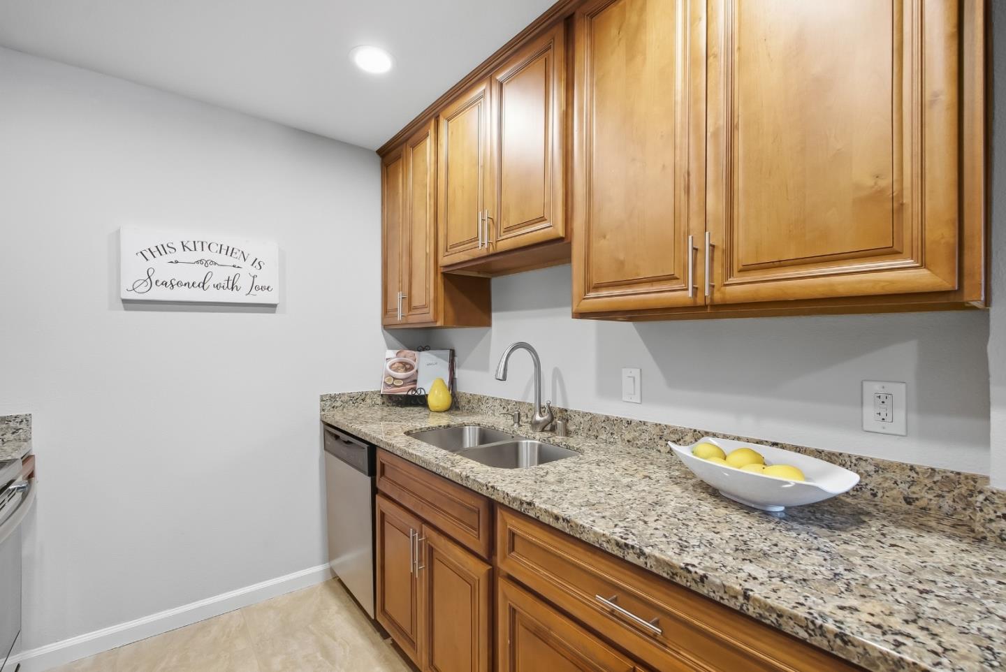 Kitchen with warm wood cabinets, granite counters, a double sink, and a bowl of lemons.