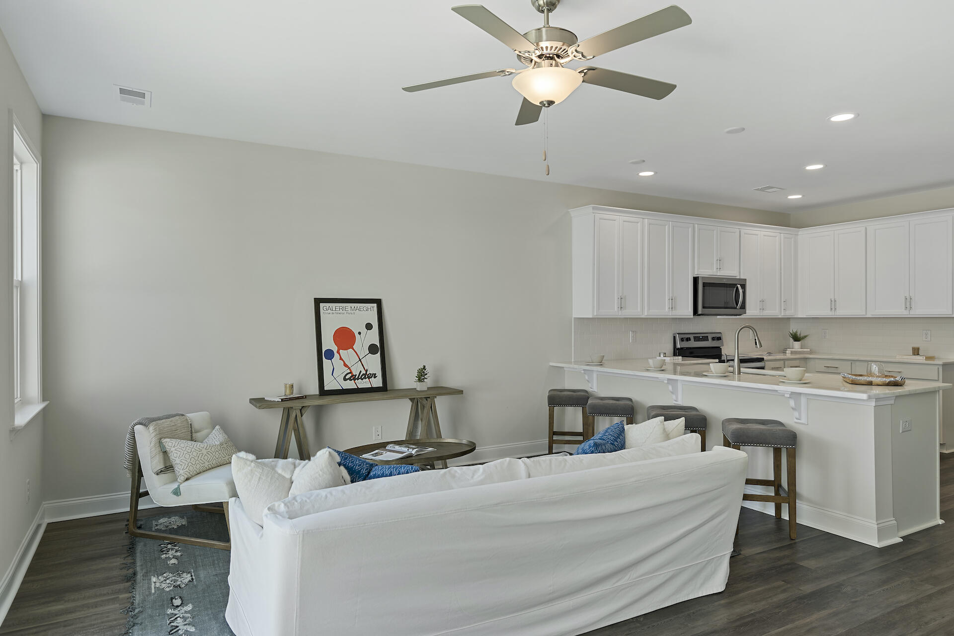 Open-plan living room and kitchen with white cabinetry, a large peninsula, and a white sofa.