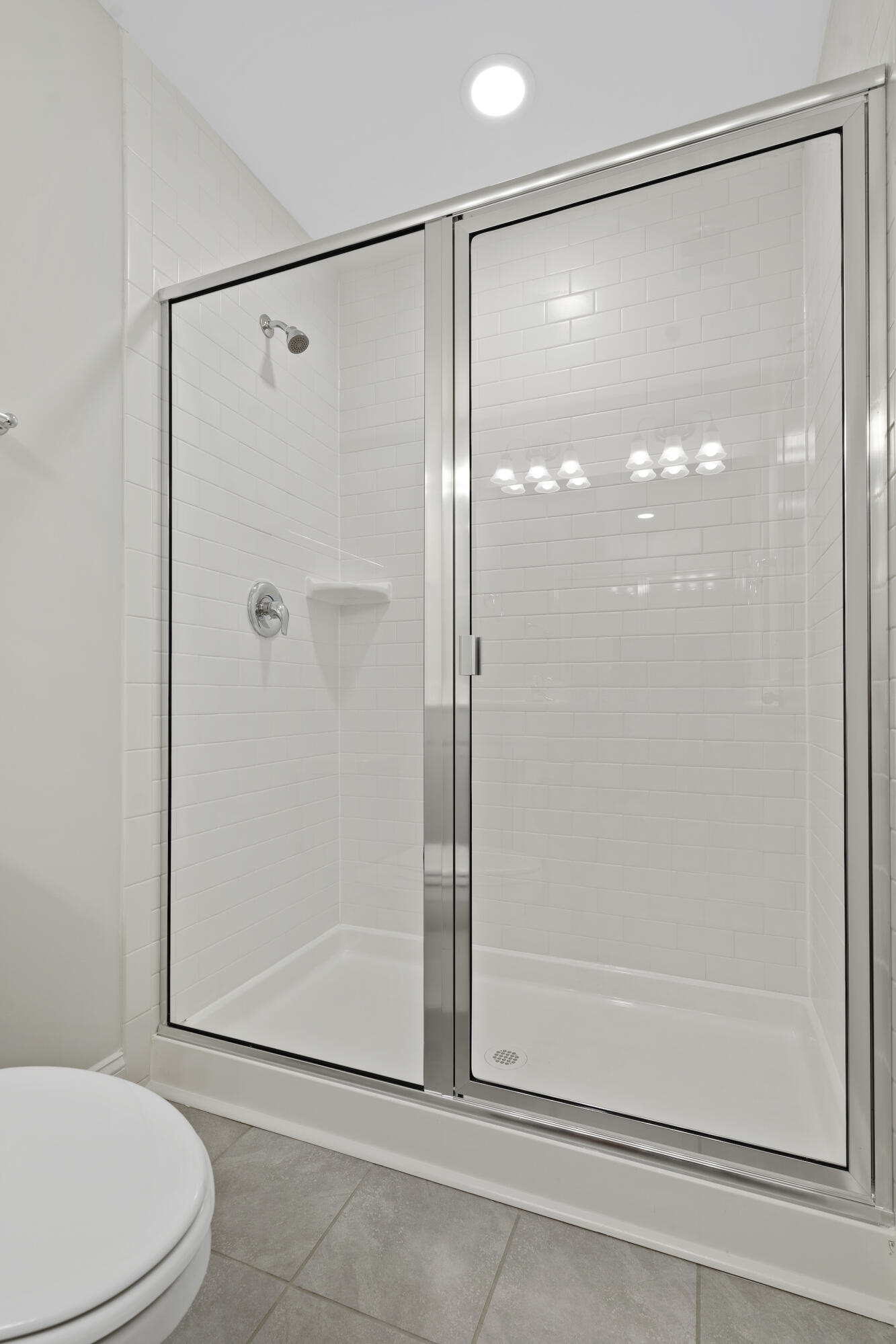 Bathroom shower with a clear glass enclosure, white subway tile, and chrome fixtures.