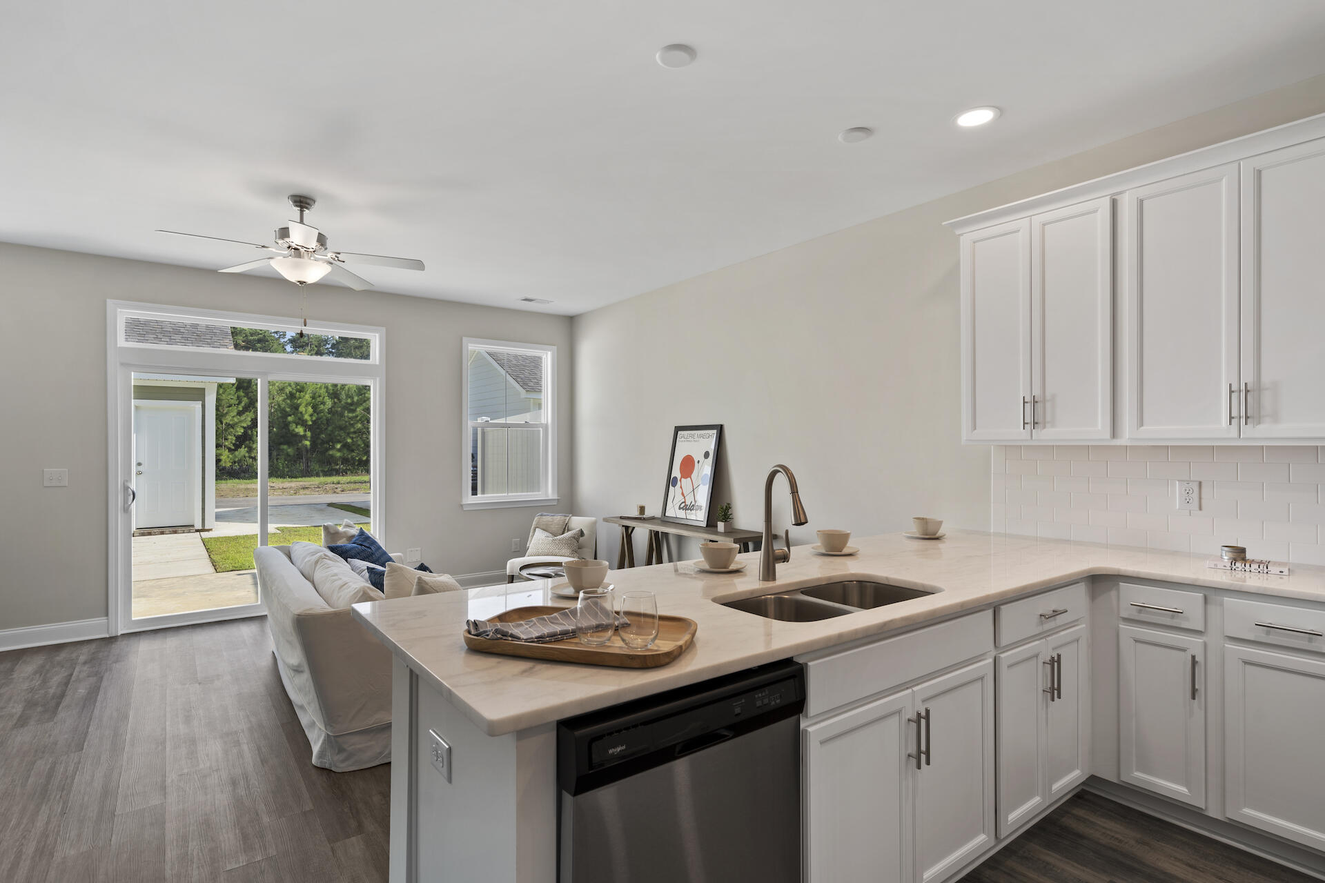 Bright white kitchen with a large island, undermount sink, and sliding glass door to the yard.