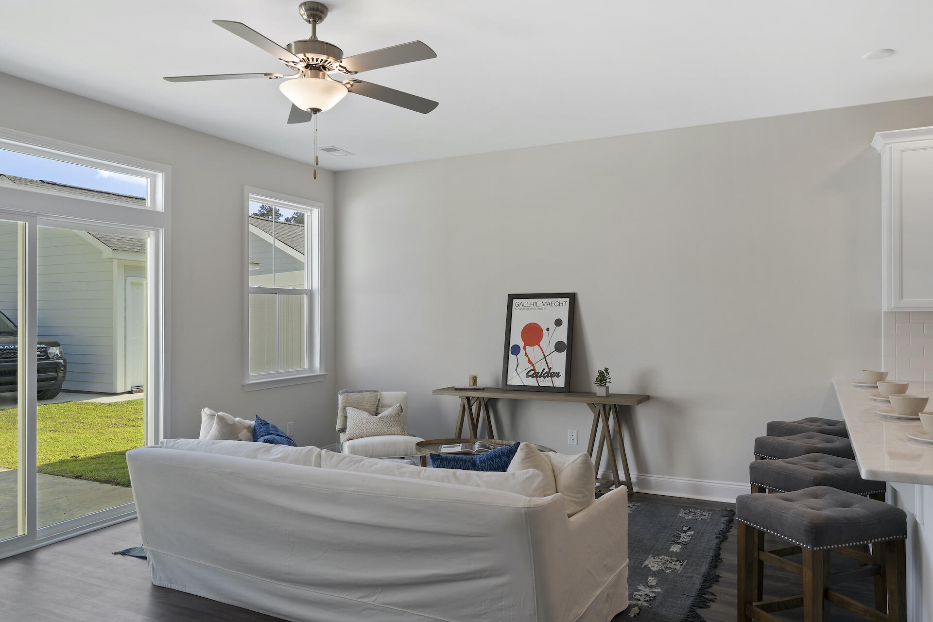 Furnished living room with a white sofa, ceiling fan, and sliding glass doors to the yard.