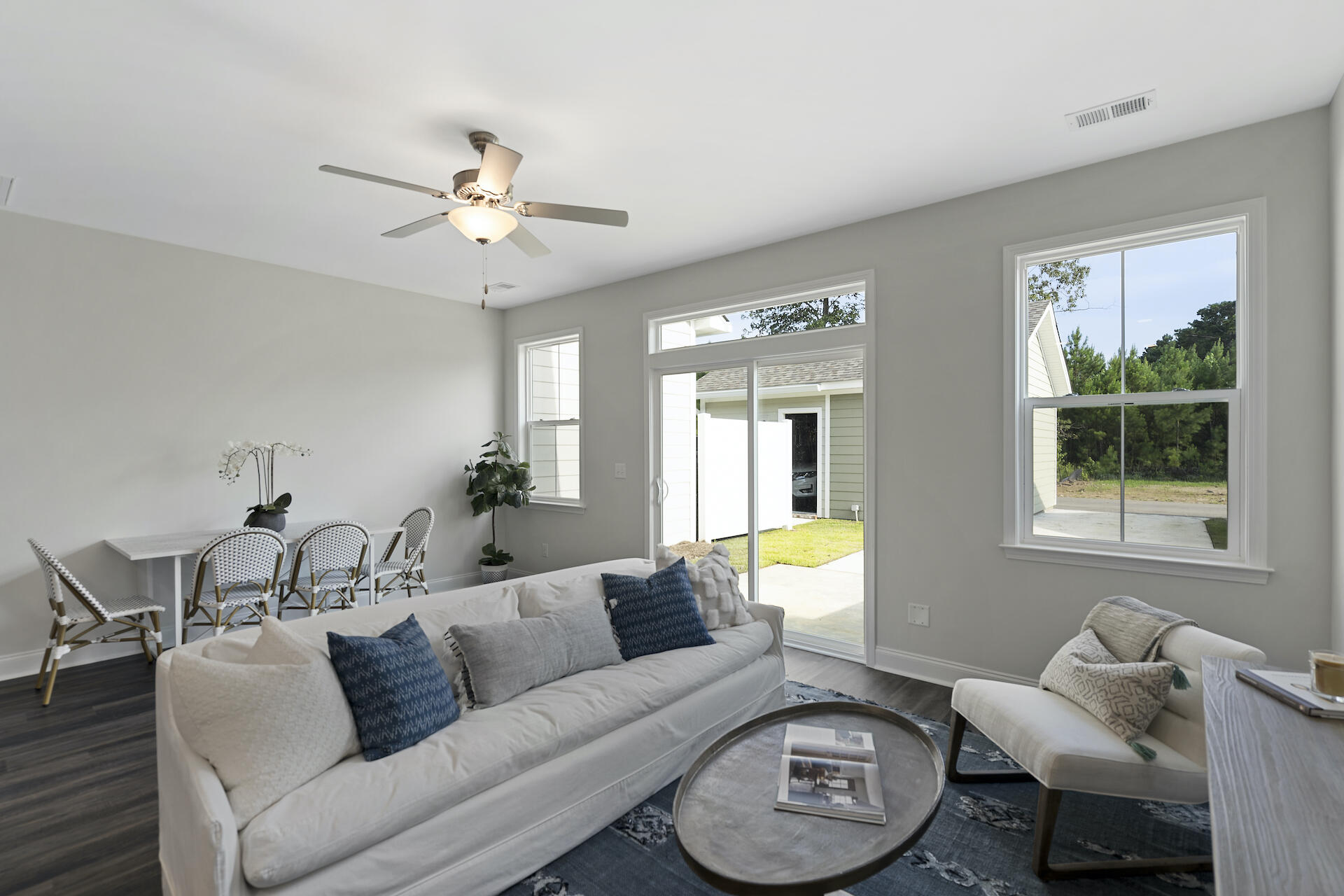 Living room with a white sofa, blue pillows, dining nook, and sliding glass door to the patio.