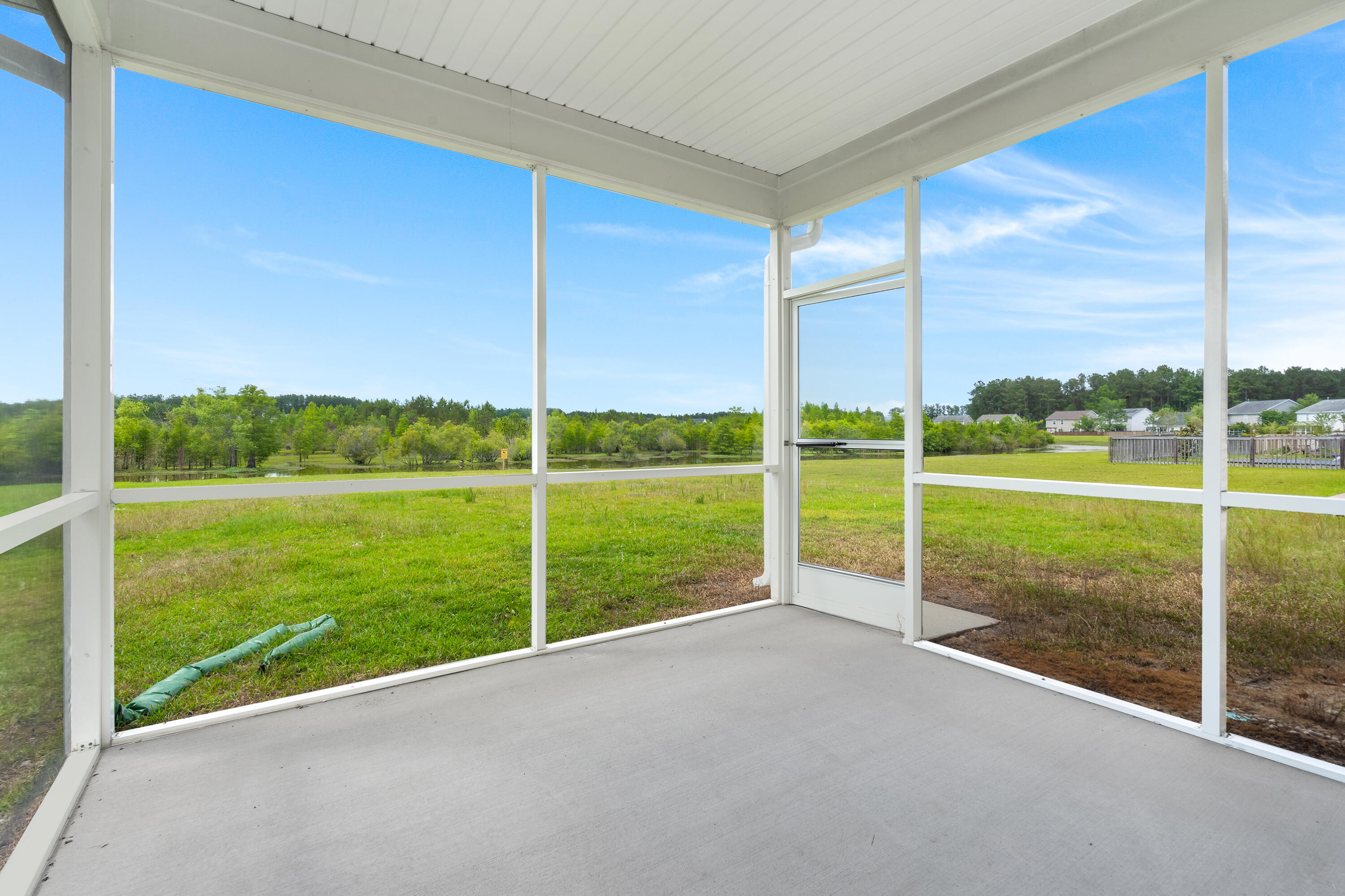 Screened porch overlooking a wide green yard and tree line.