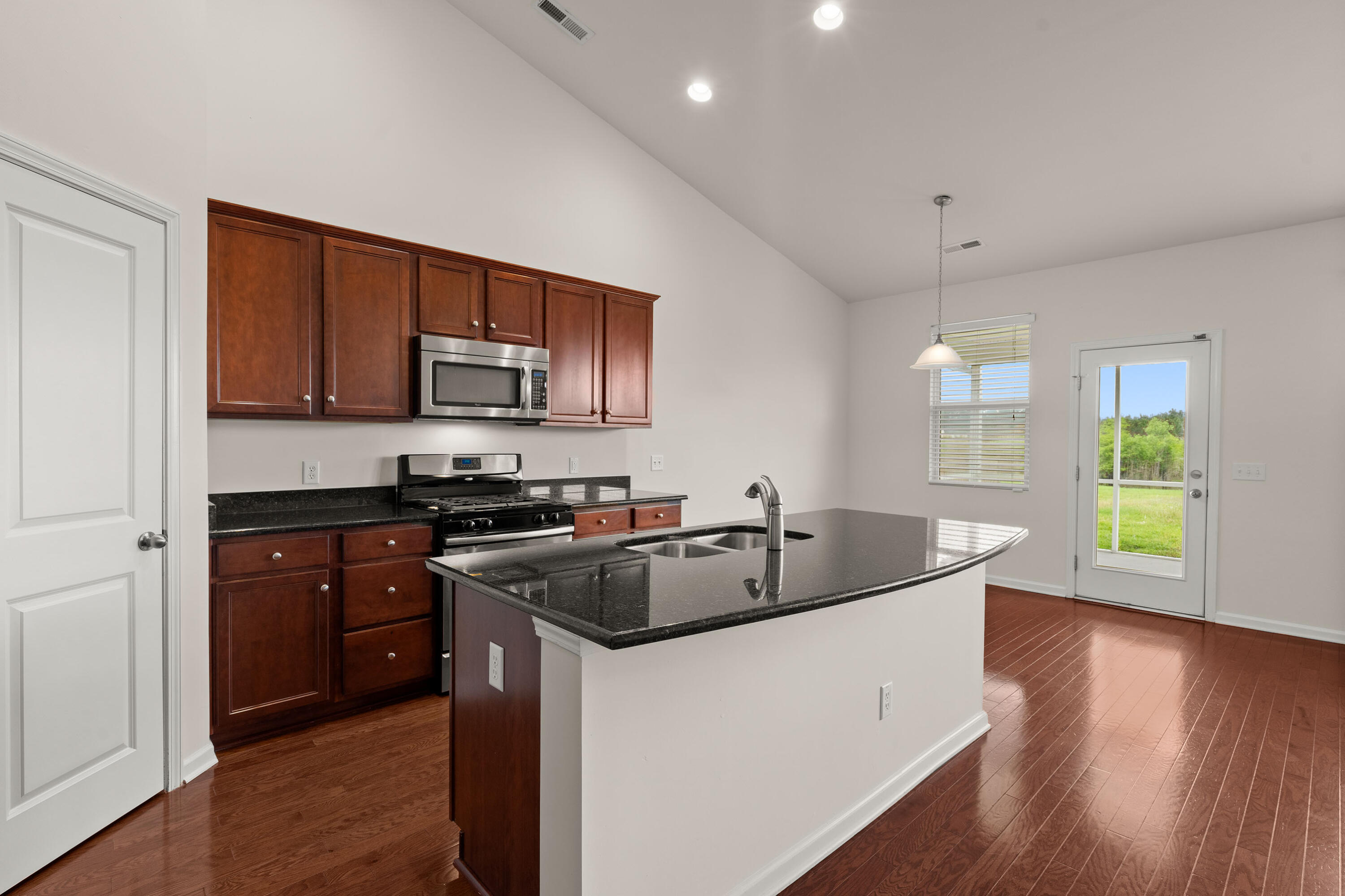 Kitchen with cherry cabinets, stainless steel appliances, and a large granite island overlooking the yard.