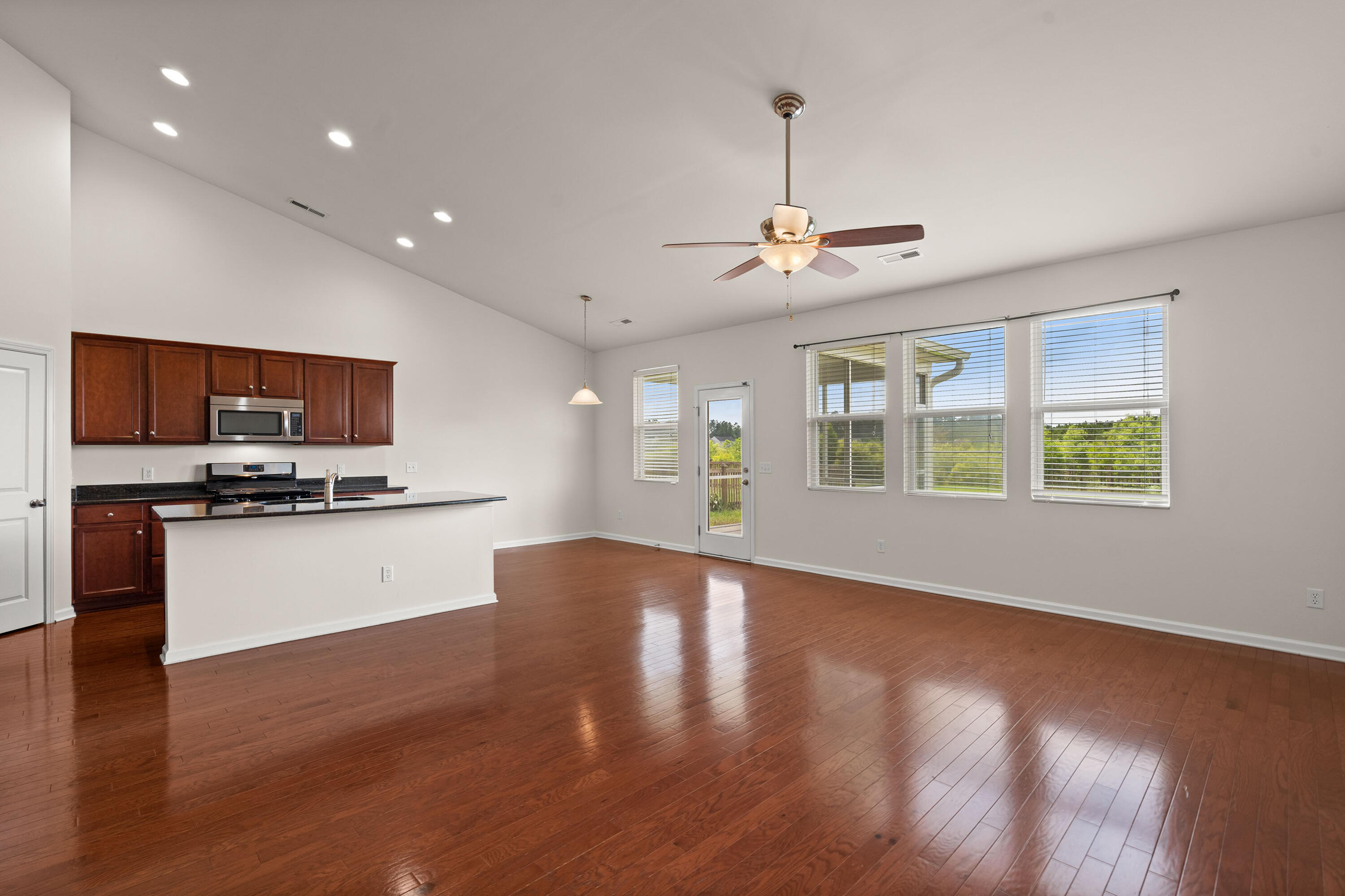 Open kitchen and dining area with dark wood cabinets, a peninsula, hardwood floors, and large windows.