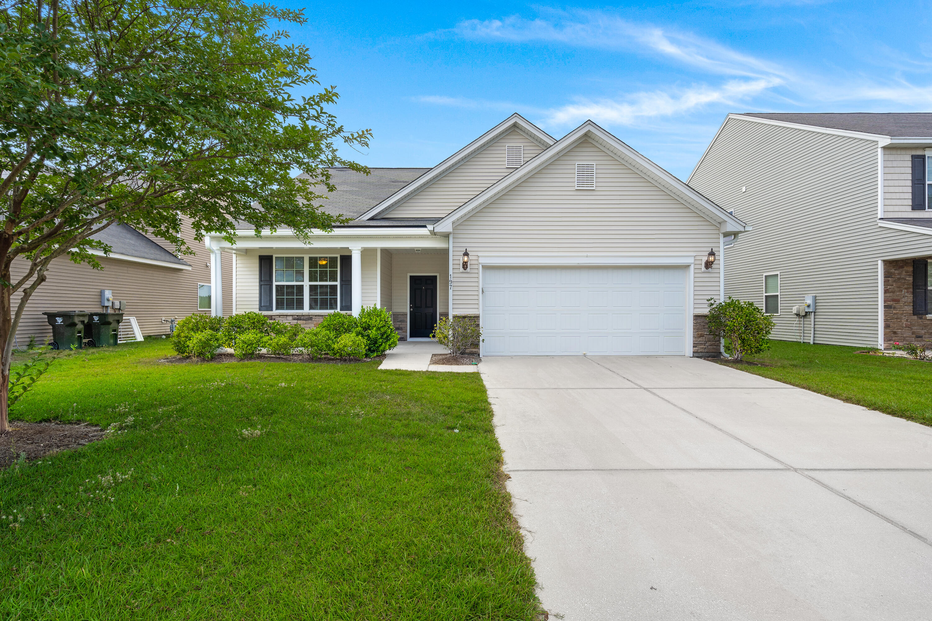 Gray single-story home with a two-car garage, covered porch, and broad concrete driveway.