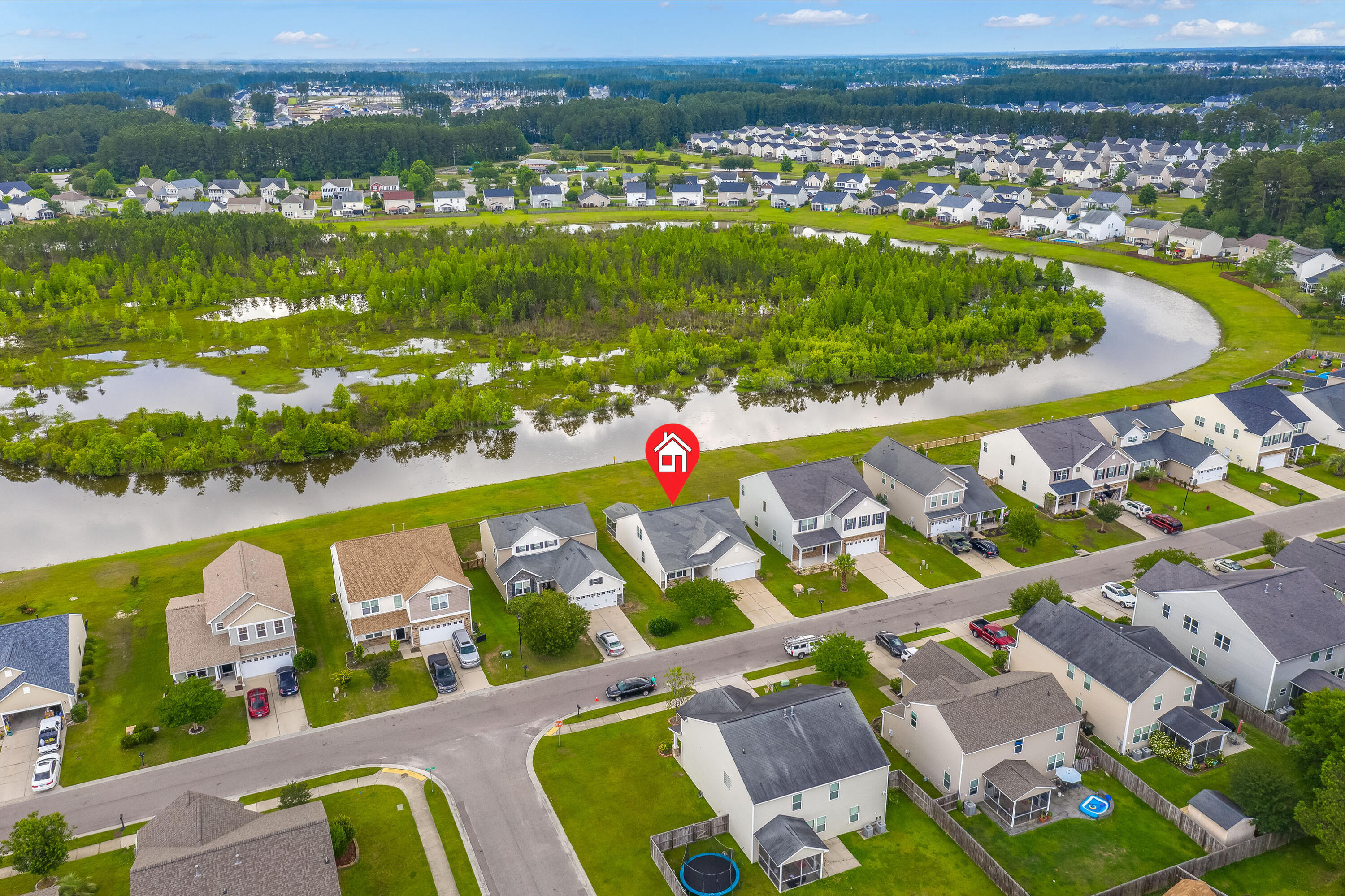 Aerial view of a home marked beside a winding pond and wooded wetland.