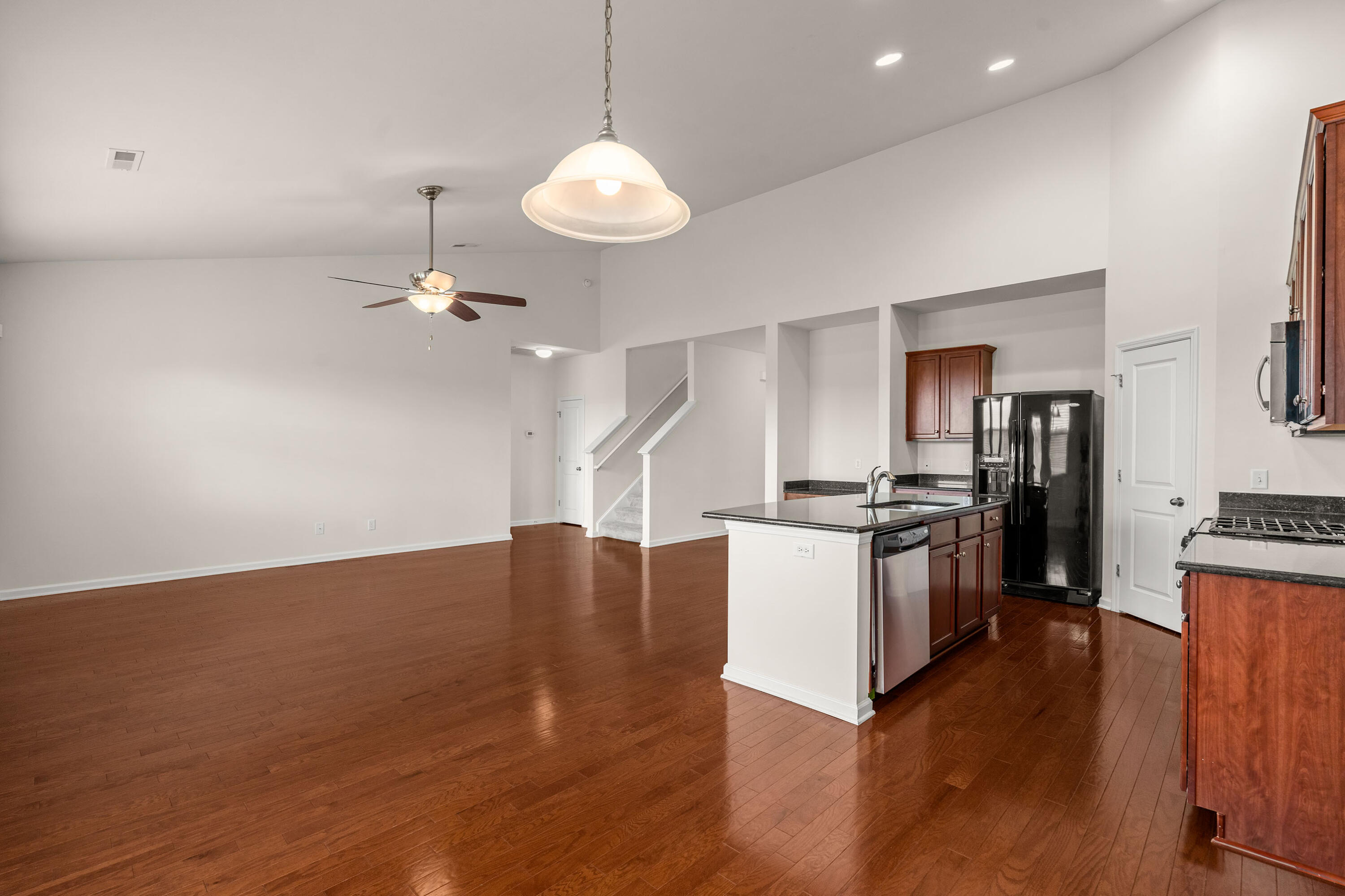 Open-plan kitchen and living area with hardwood floors, a central island, and dark wood cabinetry.