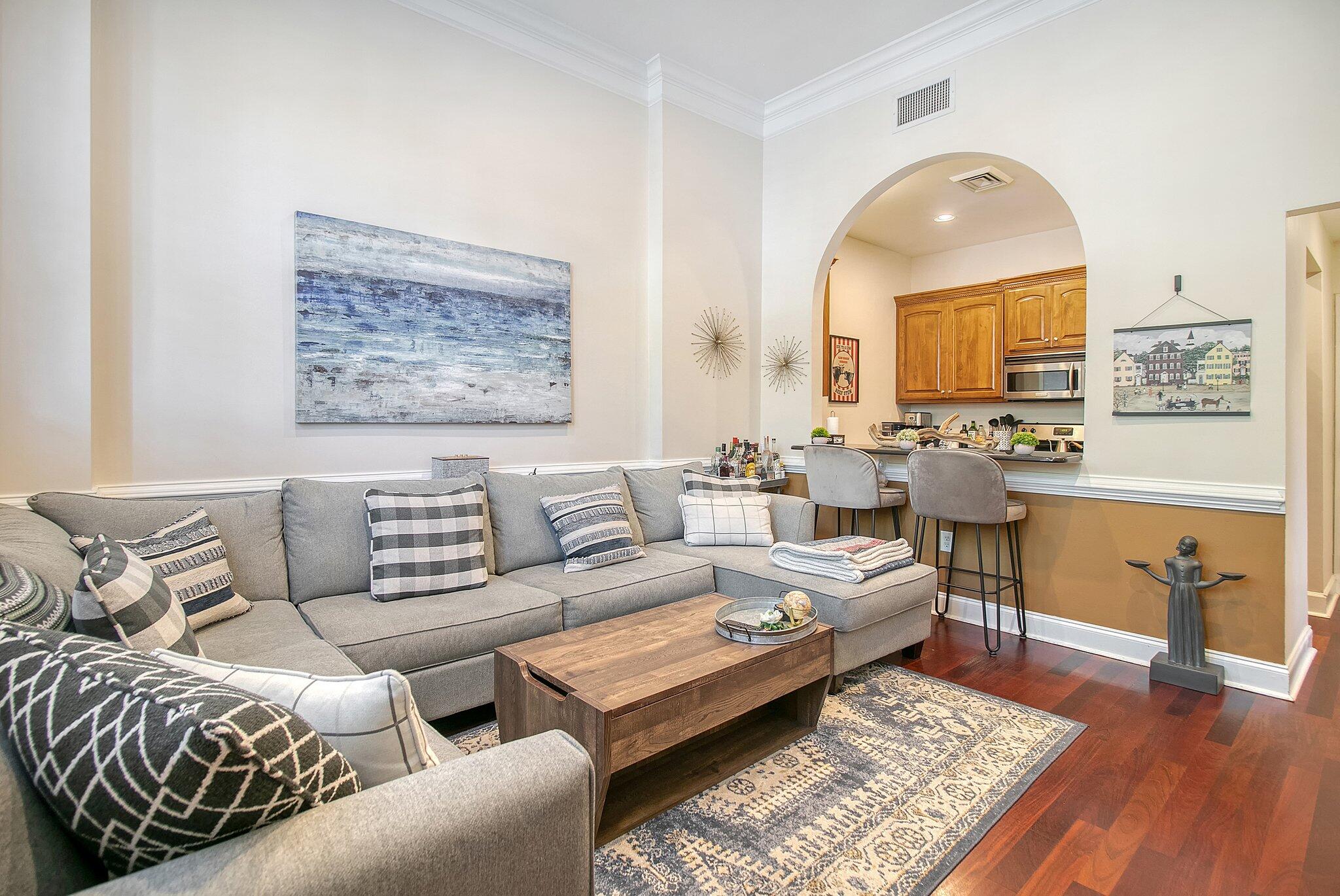Living room with a gray sectional and an arched opening to the kitchen.