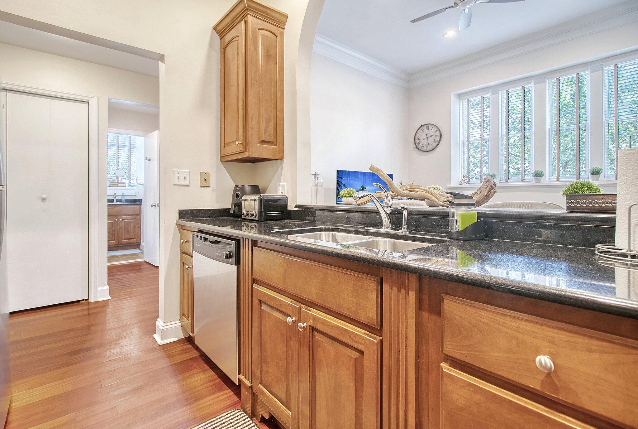 Kitchen with wood cabinets, dark stone counters, a double sink, and shuttered windows.