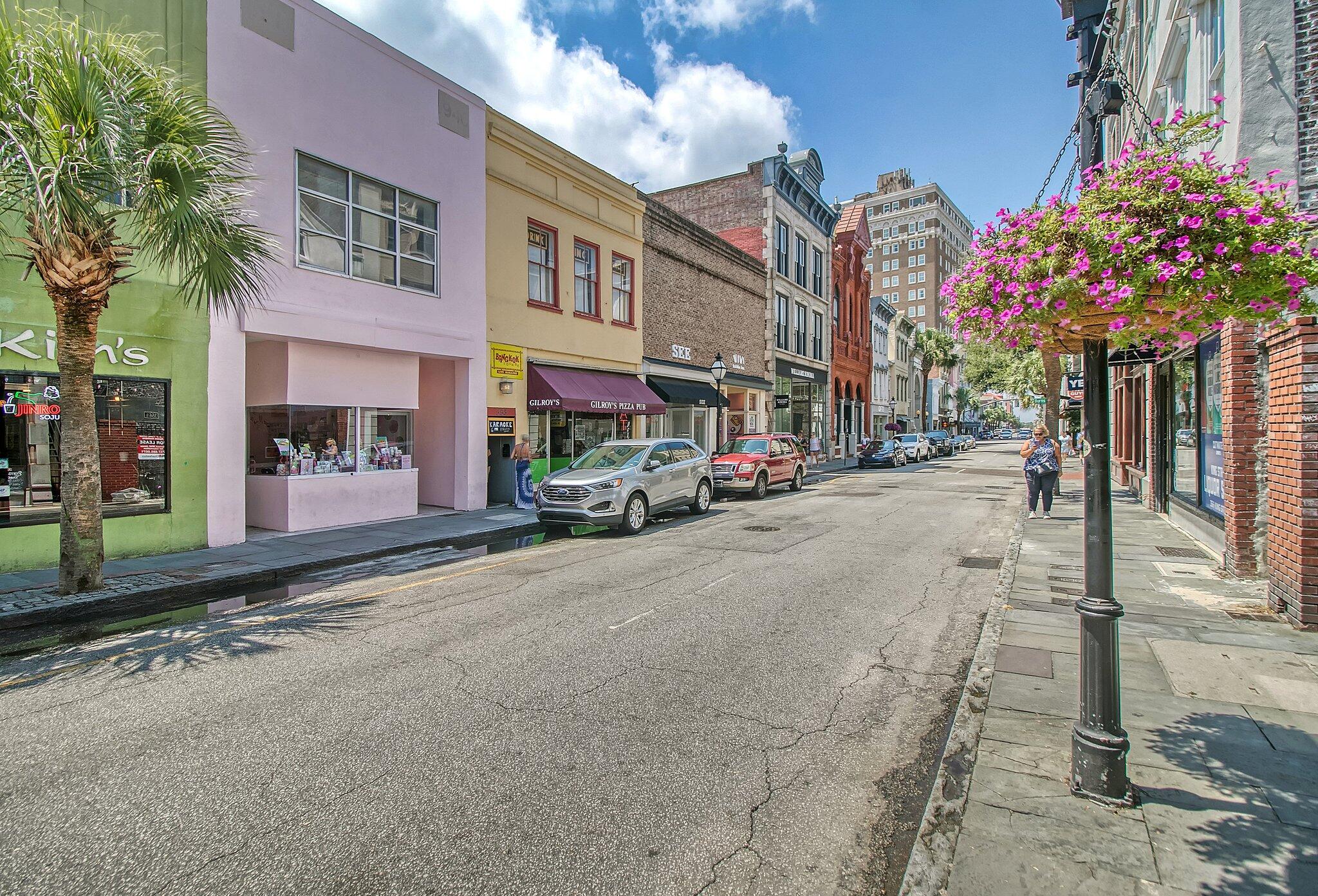 King Street streetscape with colorful storefronts, parked cars, and a hanging basket of pink flowers.