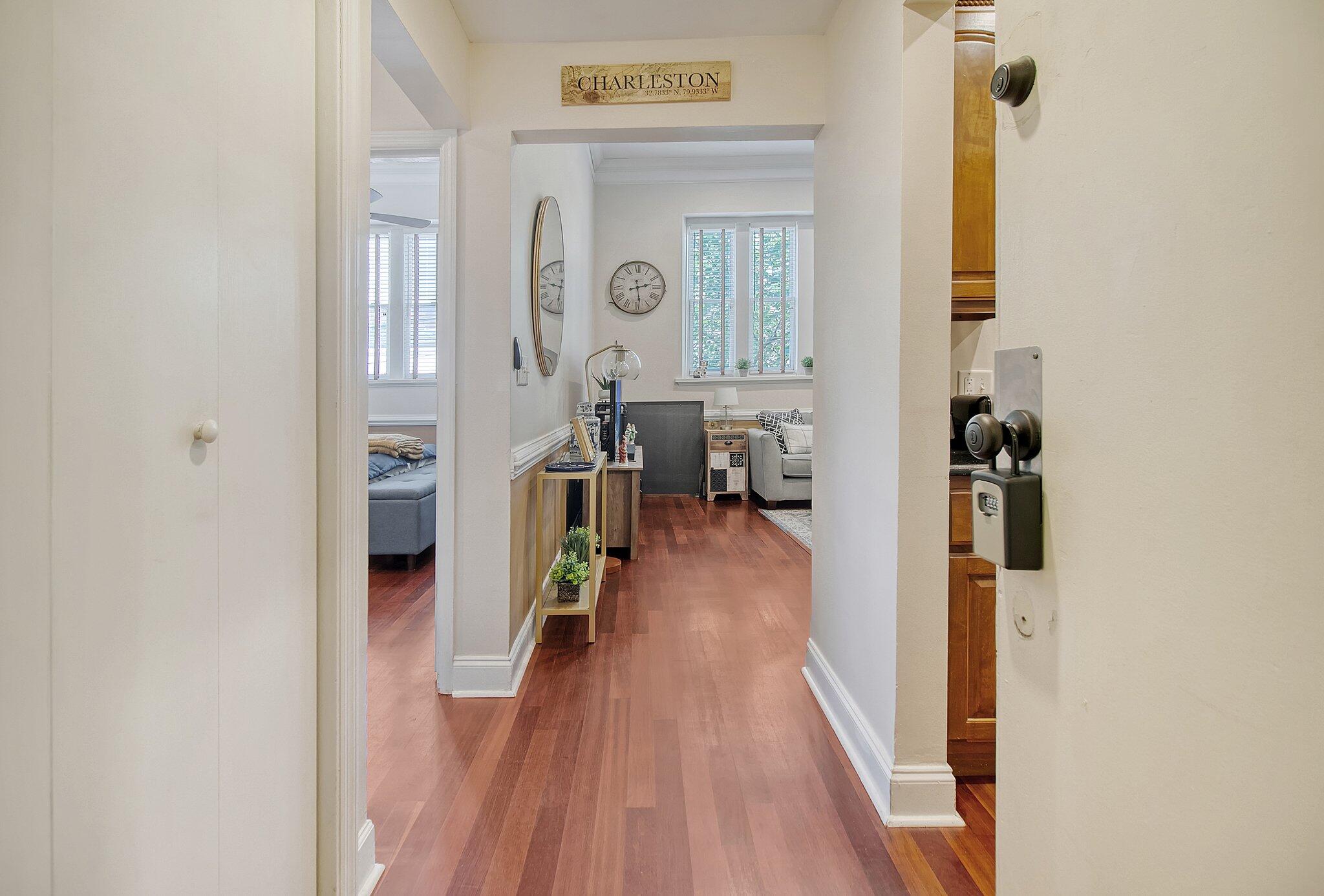 Condo entry hallway with reddish wood floors leading to a furnished living room.