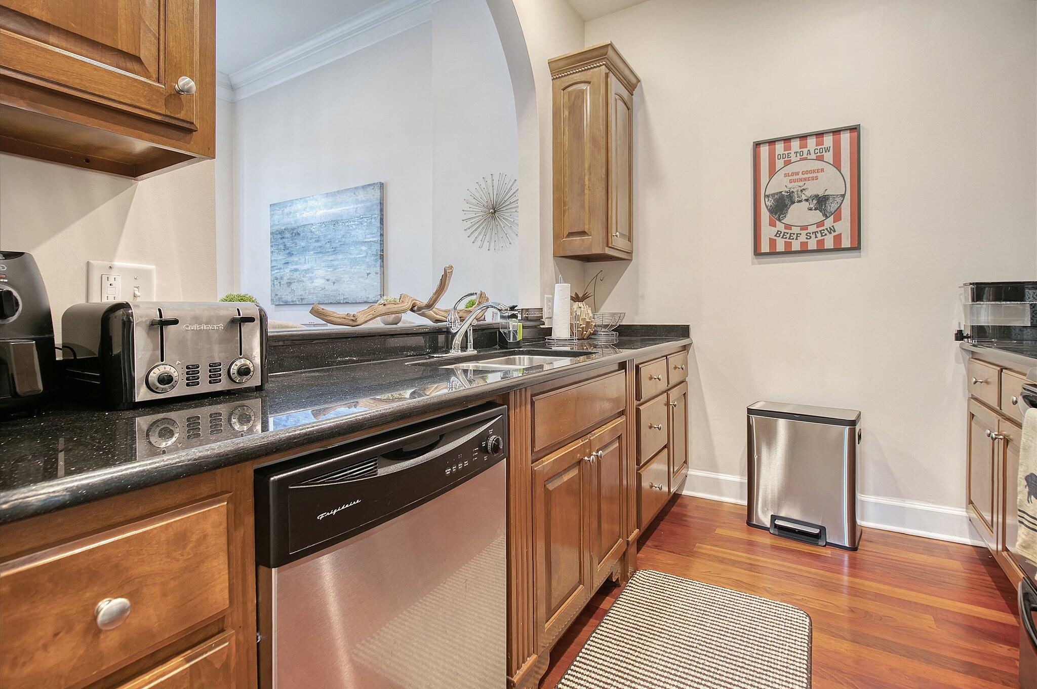 Kitchen with wood cabinets, dark granite counters, stainless steel appliances, and hardwood floors.