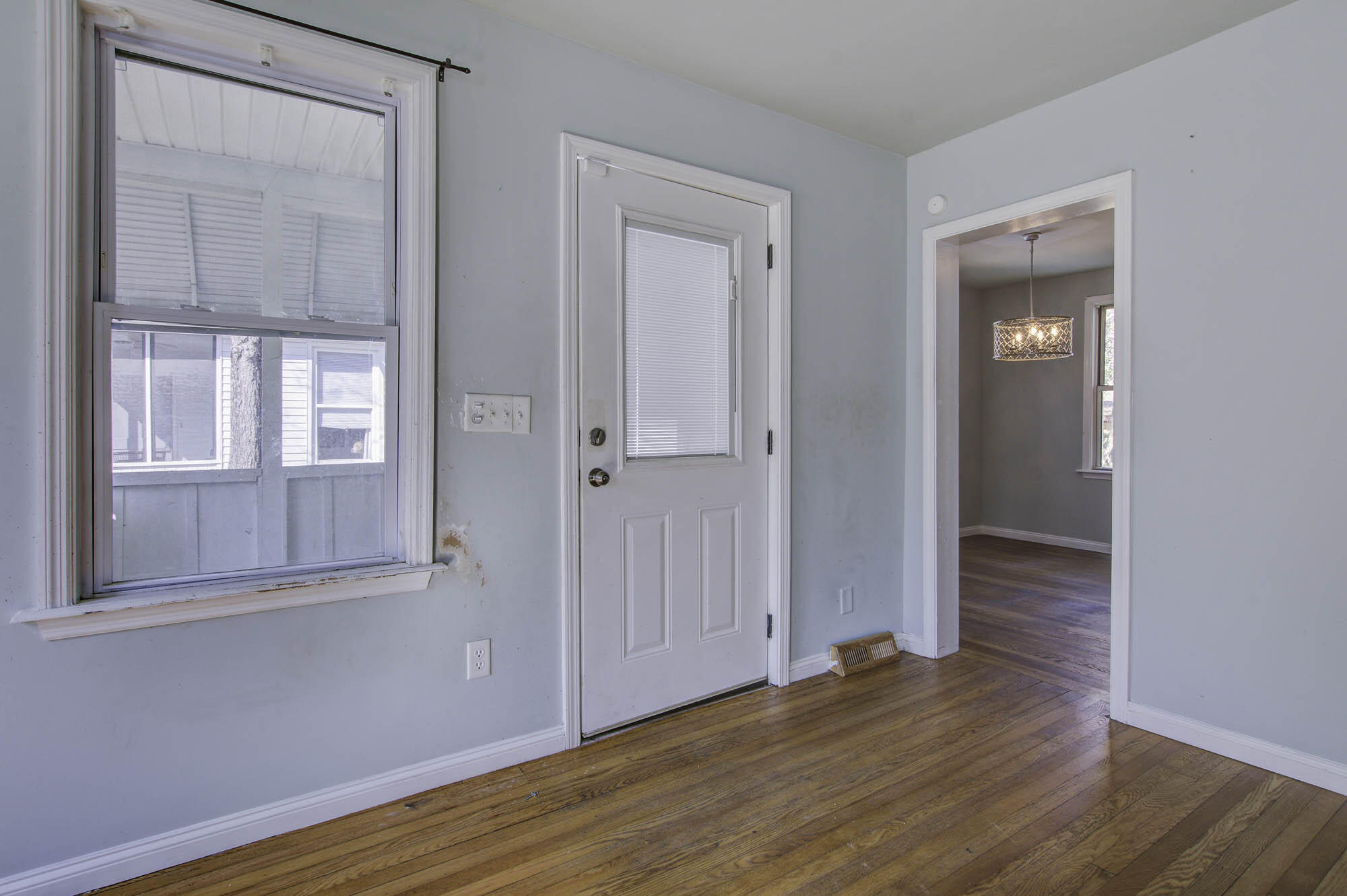 Unfurnished entry with a white front door, large window, and hardwood floors.