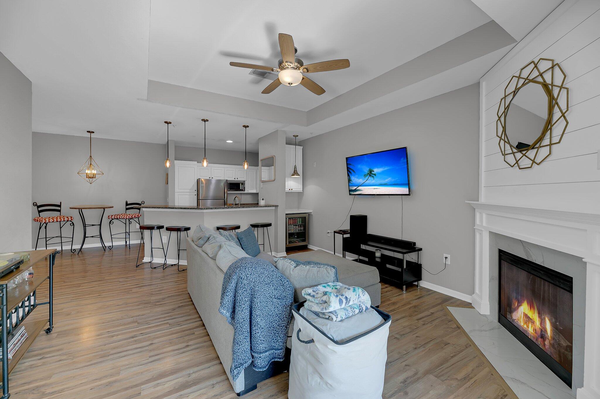 Open-plan living room with a fireplace, kitchen island, and wood-look floors.